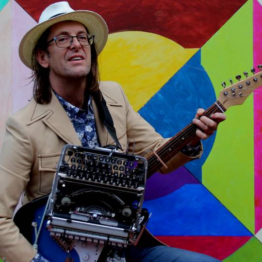 artist Richard Hold holding his guitar and typewriter hybrid